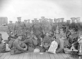 RALPH ARNOLD HENRY THOMAS (Troops from 23rd Reinforcements, 8th Battalion prior to boarding HMAT Hororata (A20). Identified, front row, sitting second from right is: 7104 Private (Pte) Leonard Cuthbert Mabbott. Also possibly in the group (identified by the name on the white kitbag at far left) is: 7040 Pte Arnold Henry Thomas Ralph.)